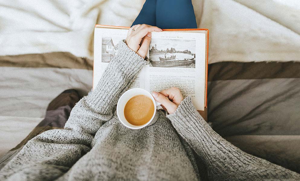 An image of a person reading and drinking coffee.