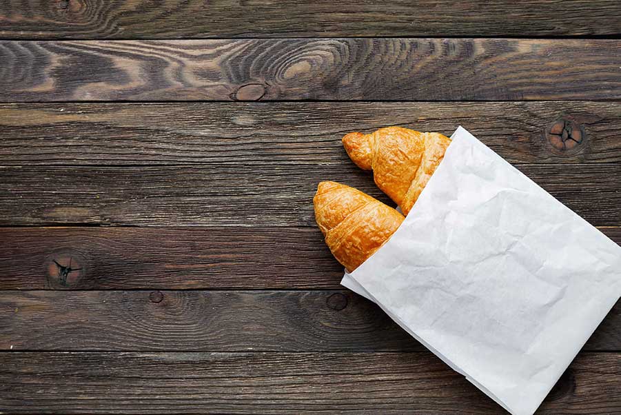 A paper bag with croissants inside.