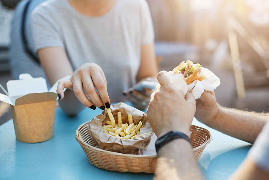 Man and woman eating fries and a burger in paper containers