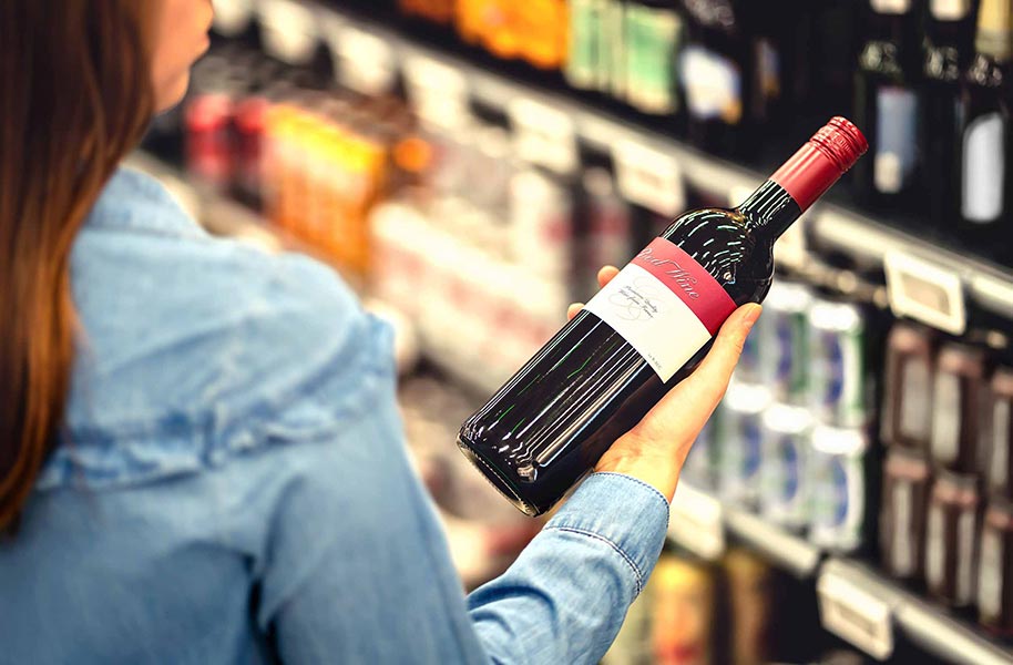 An image of a woman looking at a wine label.