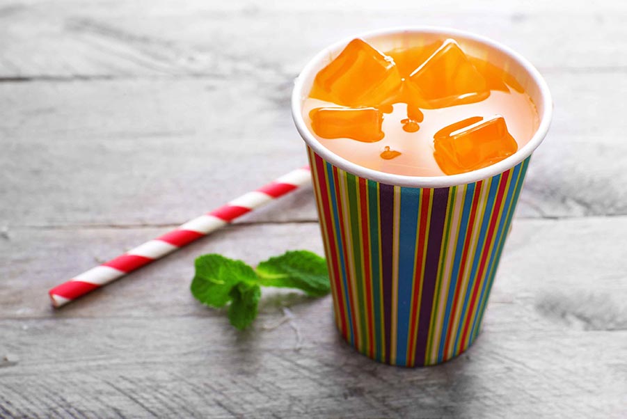 An image of punch in a paper cup sitting next to a paper straw.