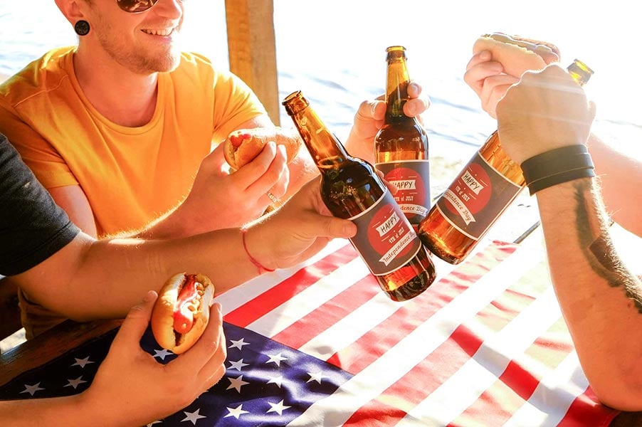 An image of friends toasting with glass beer bottles.