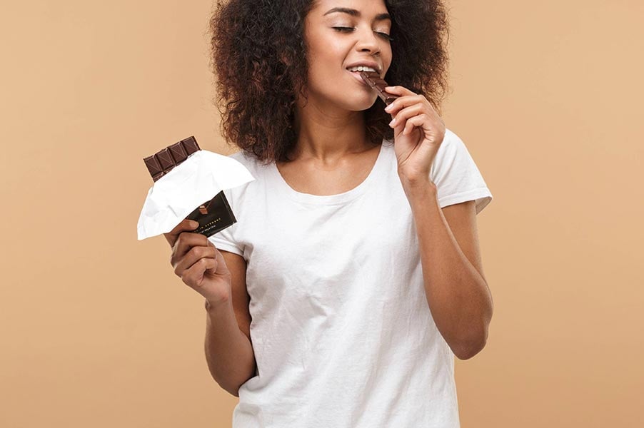 An image of a woman eating a chocolate bar.