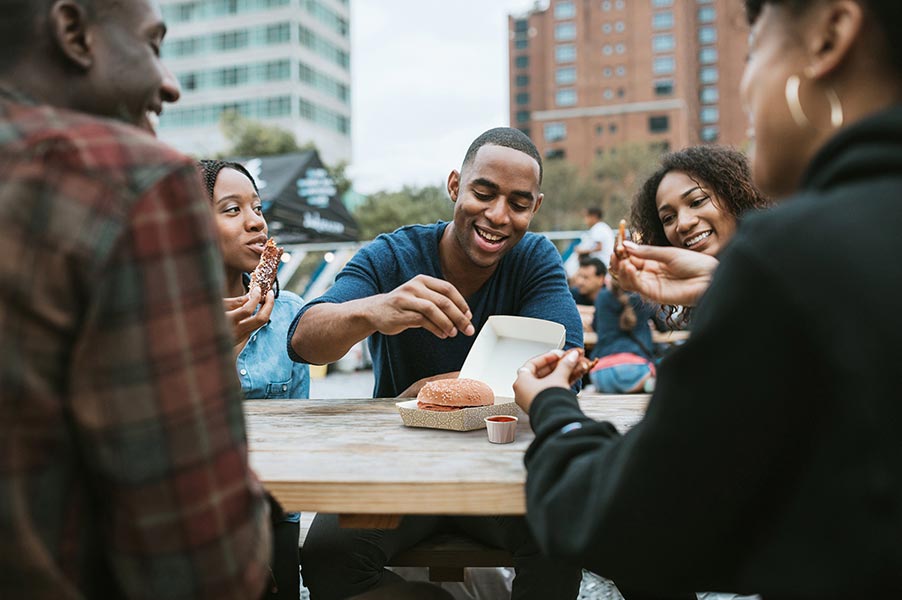 A group of friends sitting outdoors eating food.