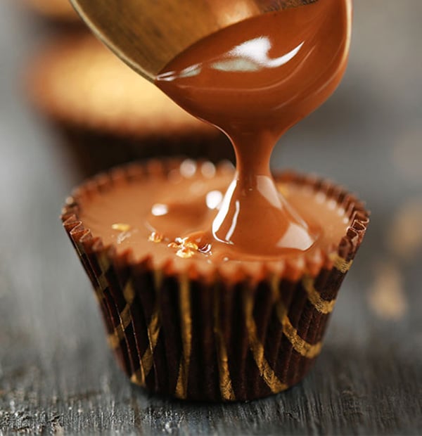 A paper candy cup being filled with melted chocolate