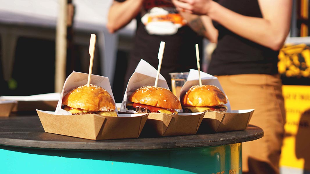 Cheeseburgers in paper trays on a table.