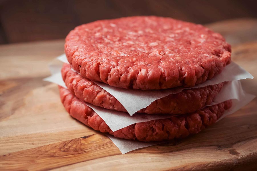 A stack of burgers separated by paper.