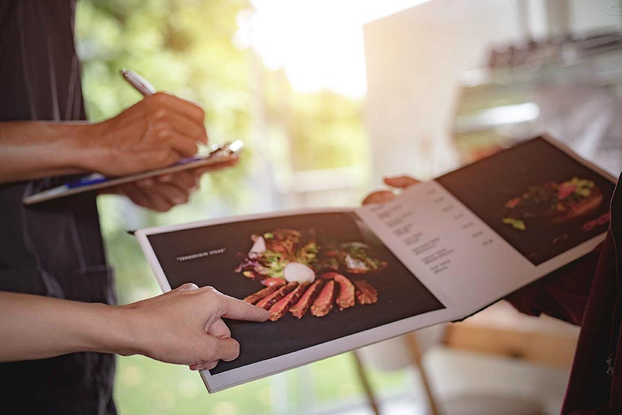 An image of a person pointing to a colorful food menu.