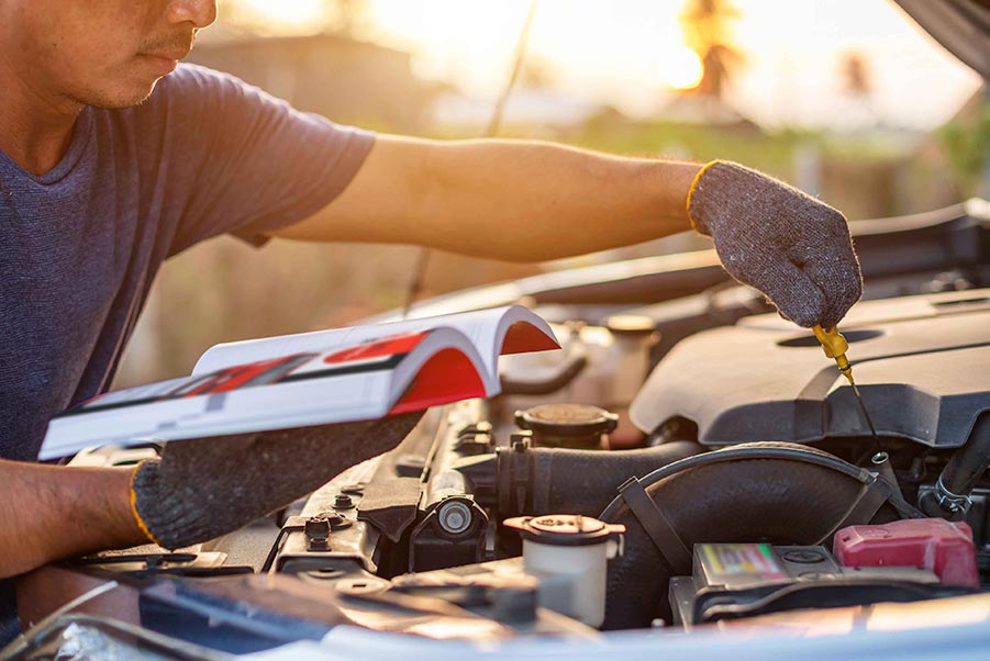 An image of a person reading a manual and changing oil.