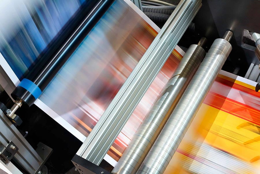 An image of paper running through a printing press.