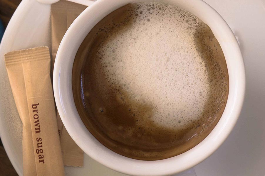 An image of a cup of coffee and sugar packets.