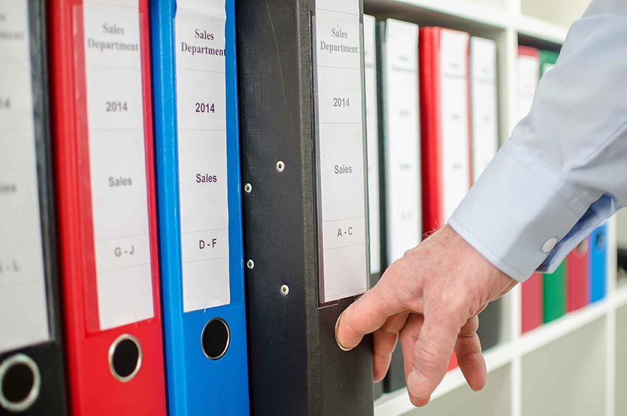 Person's hand pulling out a binder from a shelf