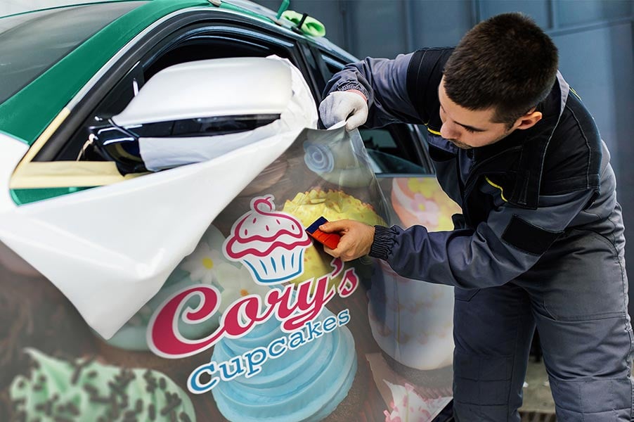 Image of a man applying a vinyl decal to a car.