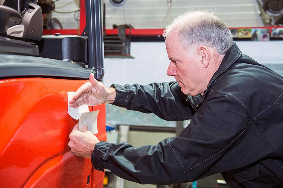 An image of a man applying a vinyl decal to a piece of equipment.