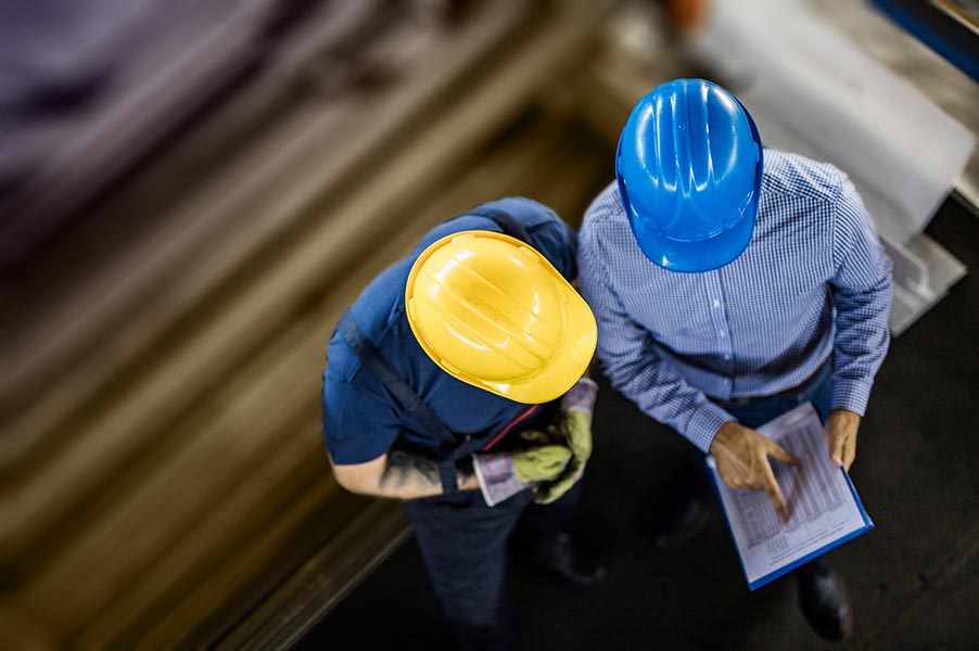 two employees in hardhats looking at a clipboard