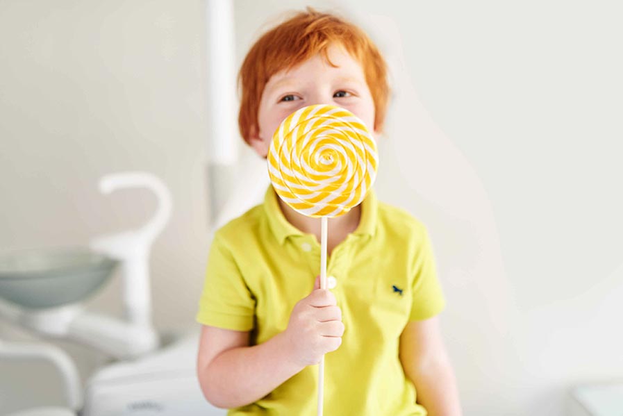 In image of a young boy eating a lollipop.