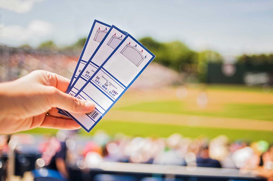 An image of a hand holding event tickets.