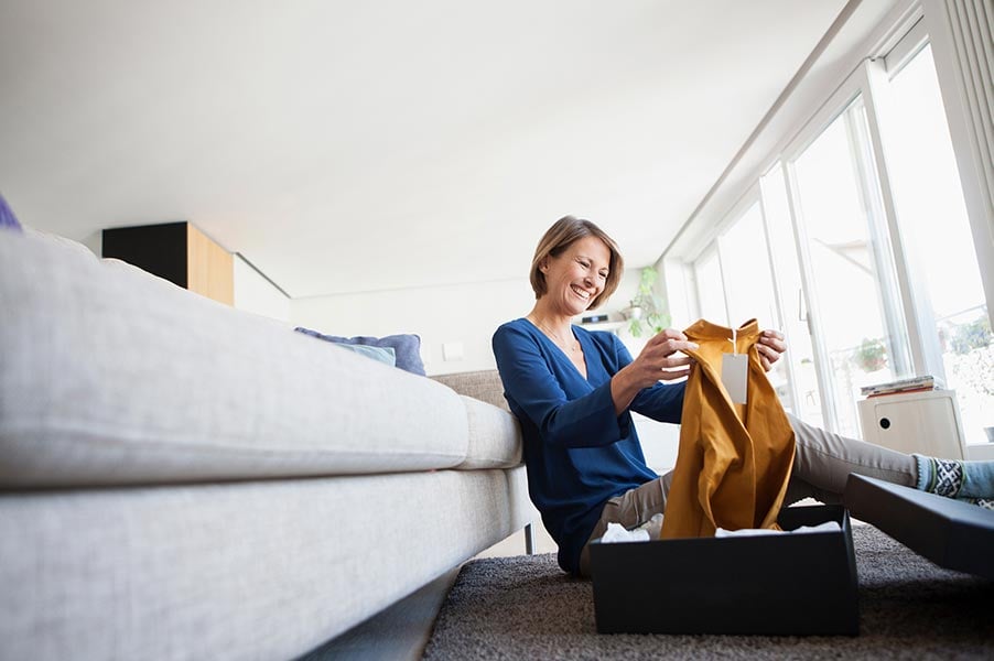 Woman sitting on the floor unboxing a new shirt