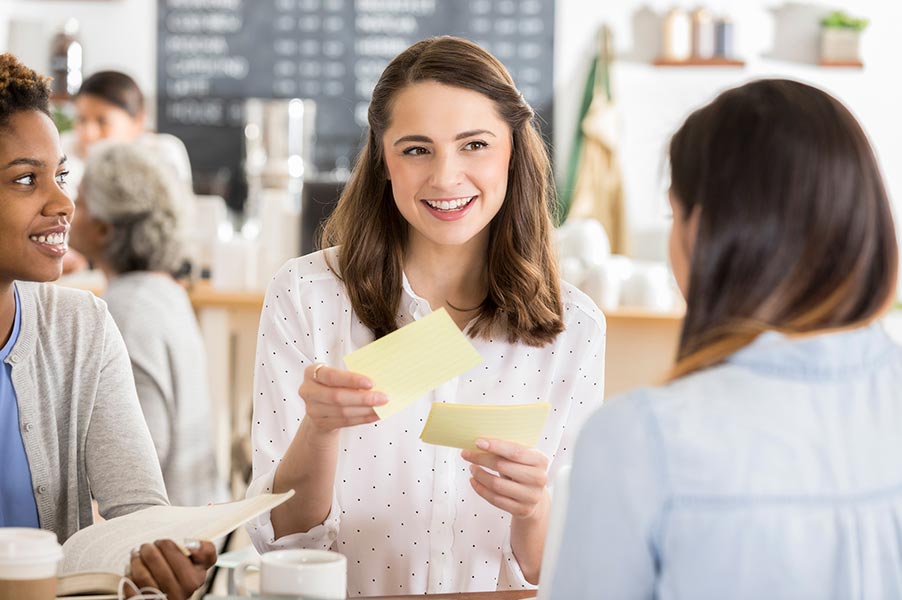 Woman holding note cards with 2 other women.